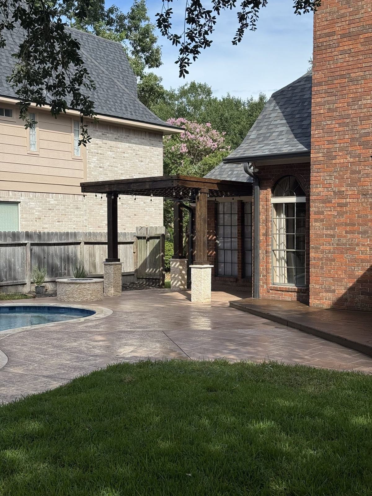 Custom pergola with stone columns over stamped patio