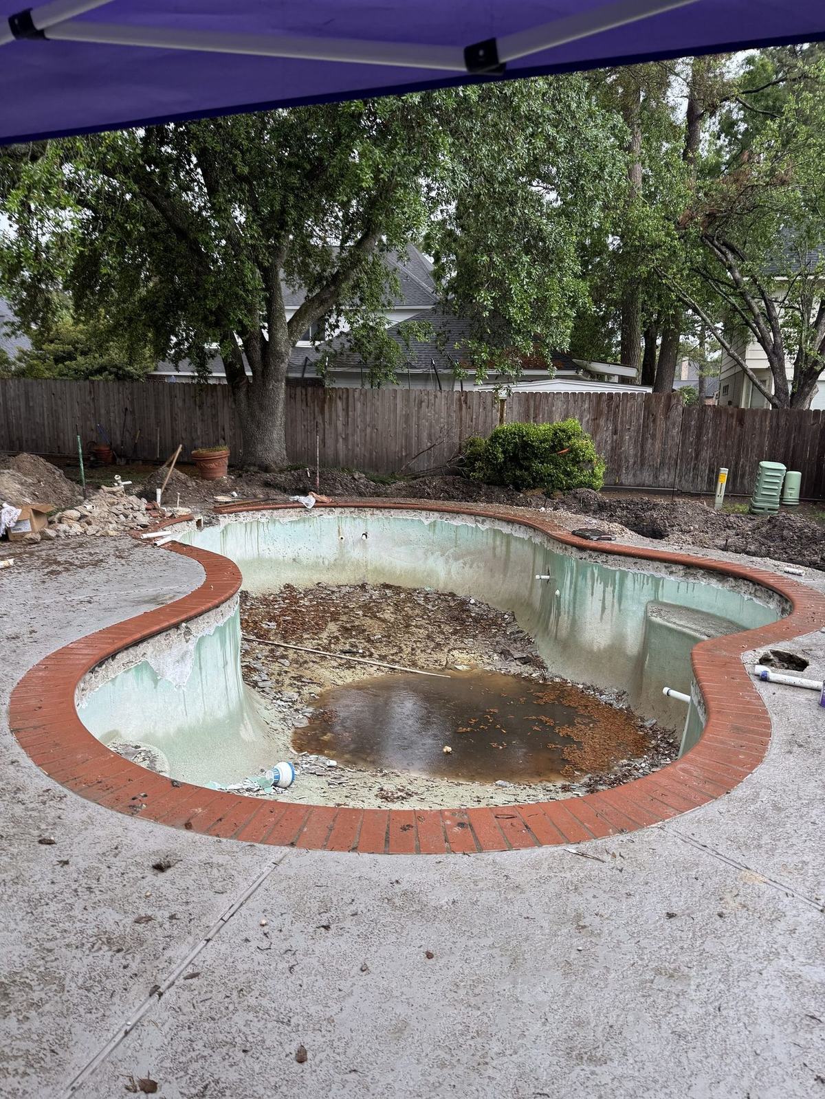 Dated pool gutted before remodel with old red brick coping